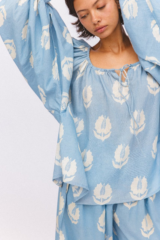 Ria Blouse Sky — outdoor lifestyle portrait, model in natural setting, sky blue block print cotton blouse, summer top, Jaipur artisan made | Daughters of India